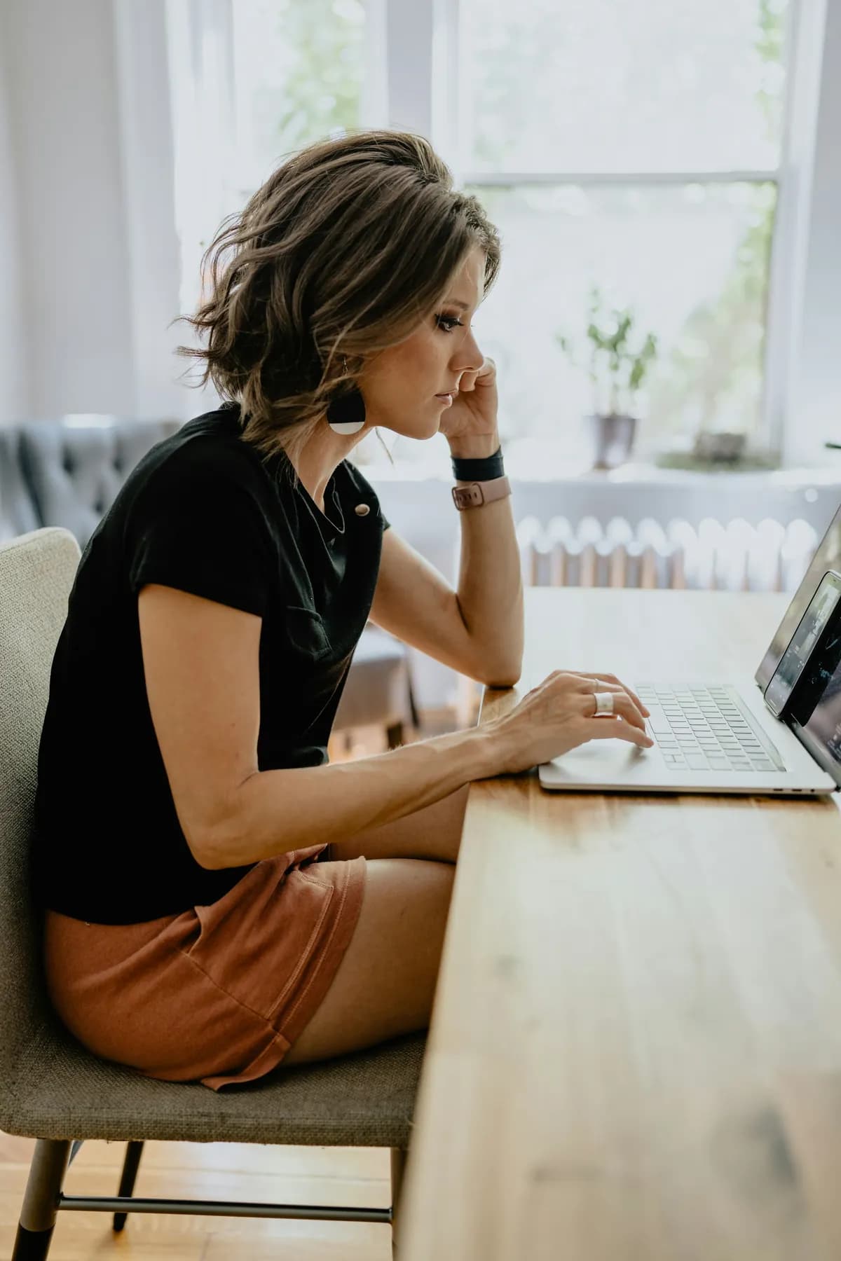 Eine Frau sitzt am Fenster und schreibt am Laptop